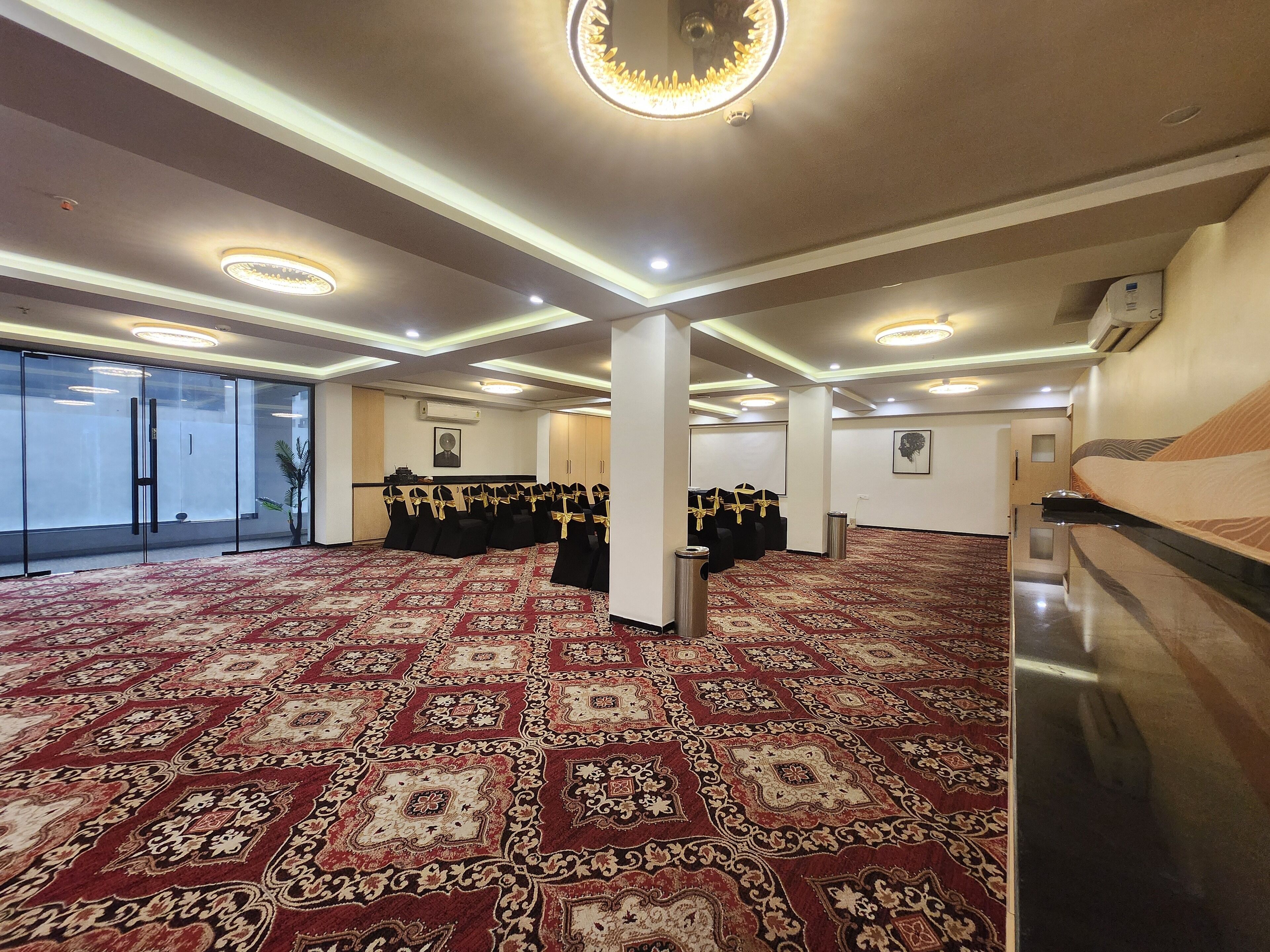 A spacious conference room with a patterned carpet, glass partitions, and rows of chairs.