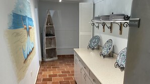 A kitchen with a tiled floor, a refrigerator, a counter with decorative plates, and a painting on the wall. - Hidden Treasure - located ON the boardwalk! (Christiansted)