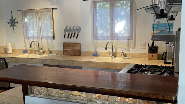 A kitchen with a central island, two sinks, a stove, and overhead lighting. - Hidden Treasure - located ON the boardwalk! (Christiansted)