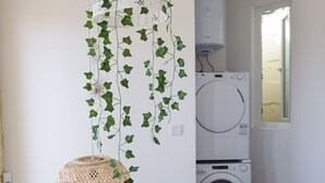 Ein Waschraum mit Waschmaschine und Trockner, einem hängenden Korbwäscheschrank und einer weißen Geländer.