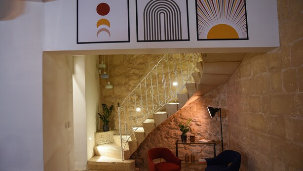 Eine Treppe mit einer Steinsäule, zwei Stühle, ein kleiner Tisch mit einer Lampe und ein gerahmtes Bild darüber.