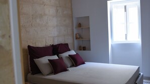 Ein Schlafzimmer mit einem Bett, einem gemusterten Boden, einer Ziegelwand und einem Fenster.
