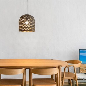 Un tavolo da pranzo in legno con quattro sedie, una lampada a sospensione e un quadro appeso al muro.