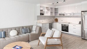 A modern kitchen with white cabinets, a built-in oven, and a stainless steel refrigerator. - St Tropez 10 - Classic Coastal Water Views (Noosa Heads)