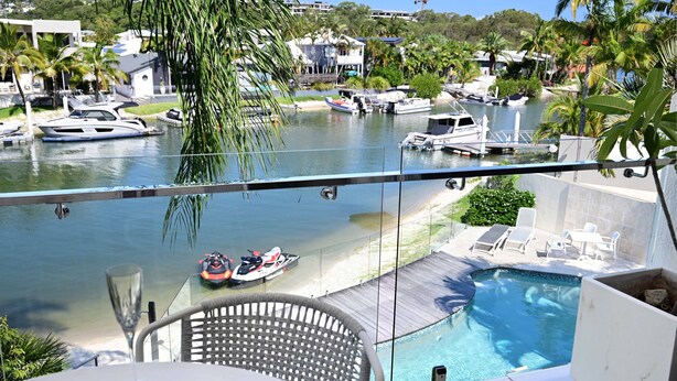 A balcony with a view of a marina, a pool, and lounge chairs. - St Tropez 10 - Classic Coastal Water Views (Noosa Heads)