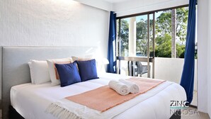 A hotel room with a large bed, a ceiling fan, and a view of the outdoors. - St Tropez 10 - Classic Coastal Water Views (Noosa Heads)
