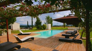 Una piscina con sillas de descanso y una pérgola.