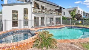 Et moderne hus med to etager, en swimmingpool, en balkon og en lukket have.