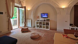 Un salon chaleureux avec un téléviseur, des meubles en osier et un coin repas aménagé pour prendre un repas.