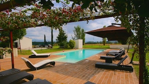 Ein Schwimmbeckenbereich mit Liegestühlen und einer Pergola.