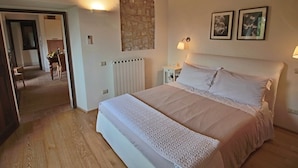 Ein Schlafzimmer mit einem großen Bett, einer Wand aus Stein, zwei Wandleuchten und einer Heizung.