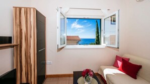 Ein Zimmer mit großem Fenster, einer Couch, einem Fernseher und einem Tisch mit Blumen.