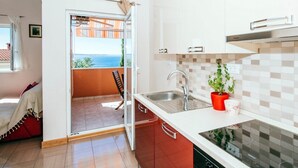 Eine moderne Küche mit Meerblick, ein Balkon mit Stuhl und ein Blumentopf auf der Arbeitsfläche.