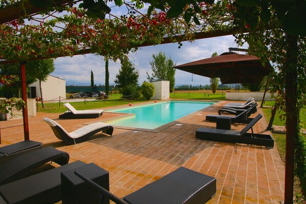 Ein Schwimmbecken mit Liegestühlen und einer Pergola.