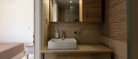 A modern bathroom with a wooden vanity, a white sink, and a mirror above it.