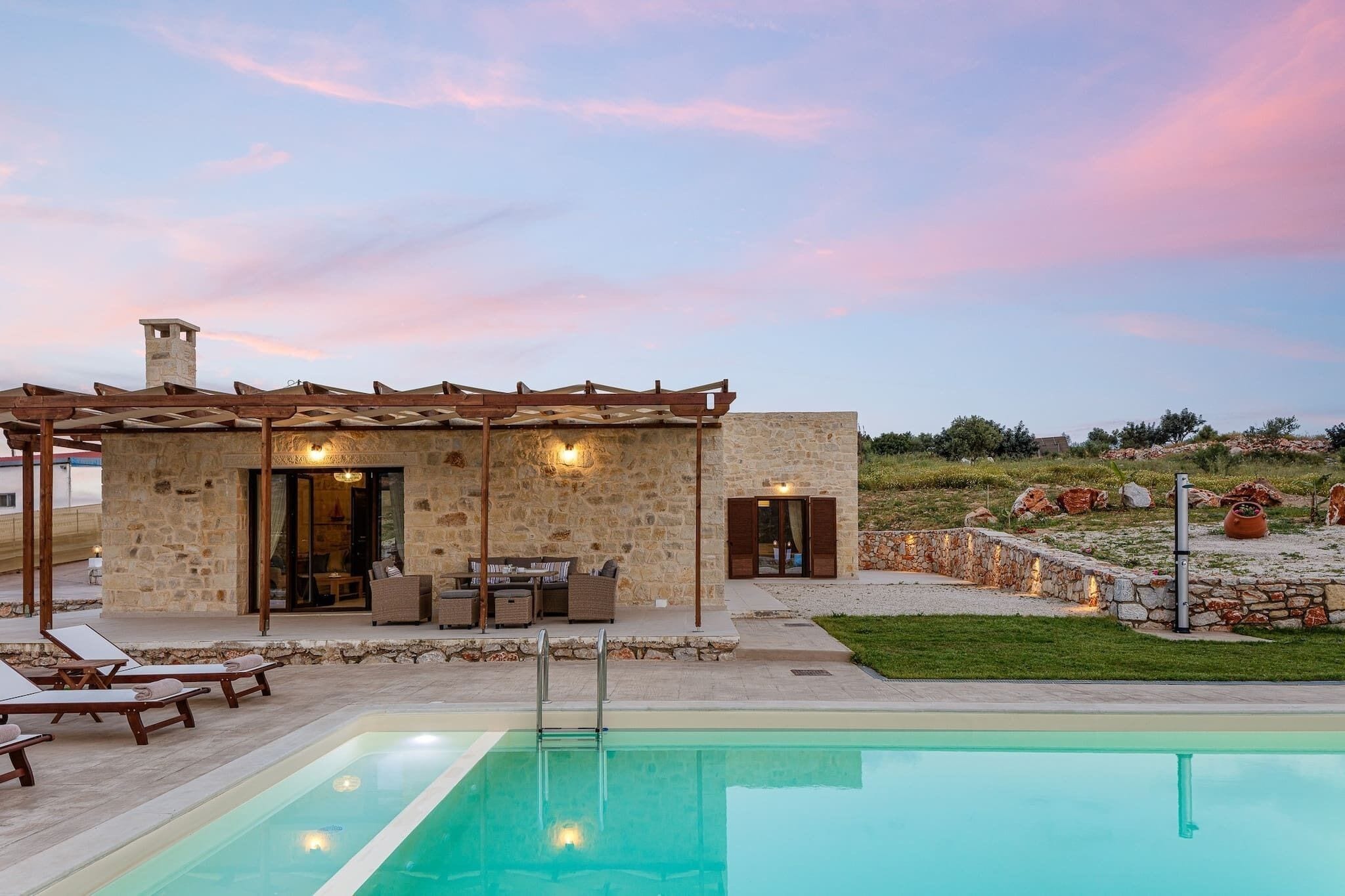 A stone building with a pool, outdoor seating, and a view of the landscape.
