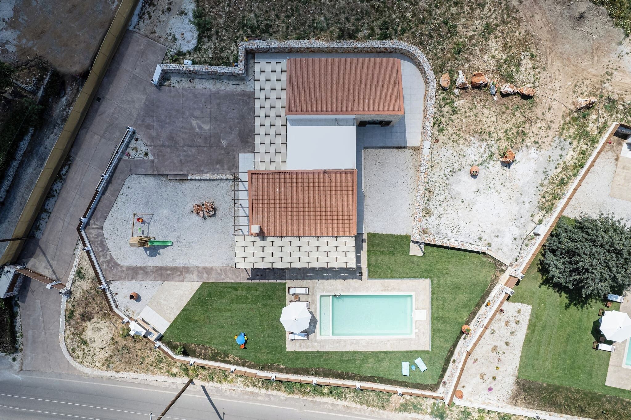 Eine Luftaufnahme eines Wohnhauses mit Schwimmbad, Terrassenbereich und umzäunter Garten.