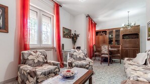 Una sala de estar con un sofá, dos sillones, una mesa de comedor y un mueble de madera.