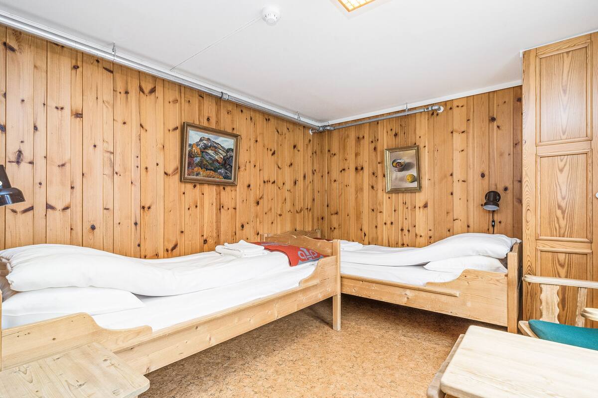 Una habitació amb dos llits superposats de fusta, un armari de fusta i una taula petita.