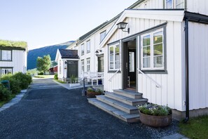 A row of white buildings with a gravel driveway leading to a front door.