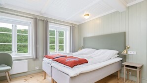 Un dormitorio con dos camas, una silla, una mesita de noche y una ventana con cortinas.