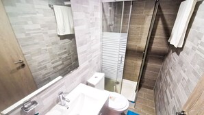 A modern bathroom with a white sink, toilet, and glass shower enclosure. - Hidden Gem City Studio (Larnaca)