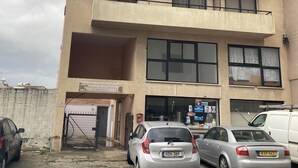 A multi-story building with a sign for "Marissa Court" and an address. There are parked cars in front, and a white van is parked on the right side. - Hidden Gem City Studio (Larnaca)