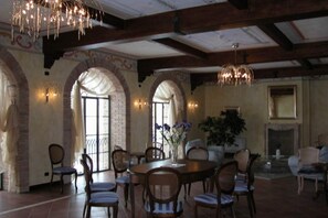 A dining area with a round table and chairs, arched brick walls, and a chandelier.