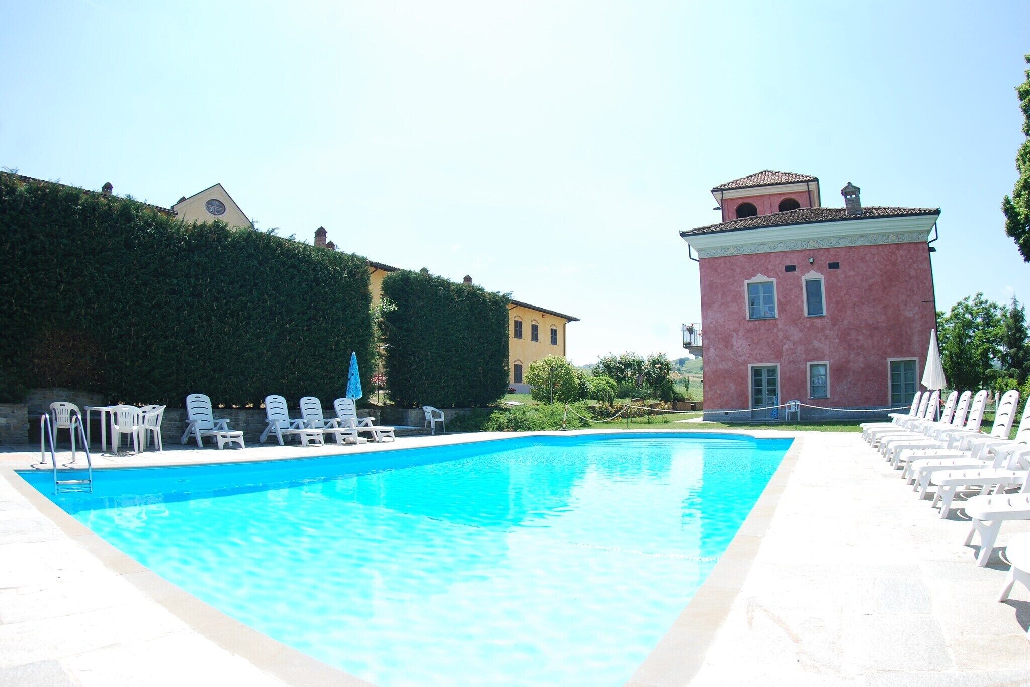 A swimming pool with lounge chairs and a building in the background.