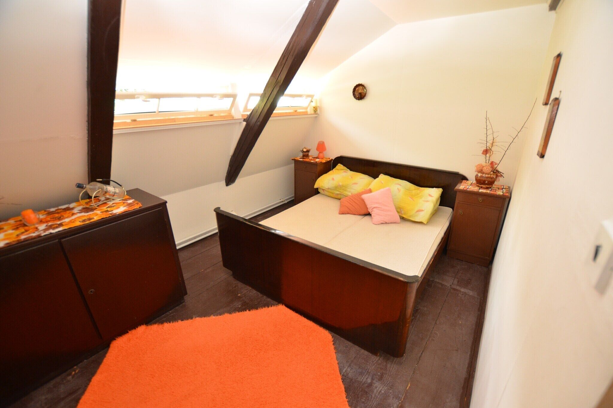 Ein kleines, gemütliches Schlafzimmer mit Bett, Kommode und Fenster.