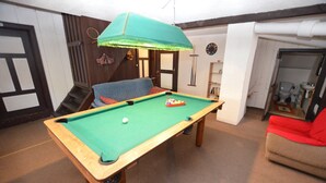 A pool table in a room with a staircase, a red chair, and a clock on the wall. - Family Chalet with Garden (Krásná Lípa)