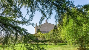 A house with a brick exterior, surrounded by a grassy lawn and trees.