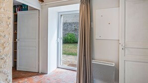 A room with a sliding glass door leading to a garden, a white door, and a radiator. - Farmhouse in Yèvre-le-Châtel with Heated Pool (Yèvre-la-Ville)