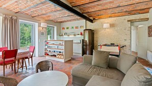 A cozy living area with a brick ceiling, a sofa, a dining table, and a kitchen area with a fridge and shelves. - Farmhouse in Yèvre-le-Châtel with Heated Pool (Yèvre-la-Ville)