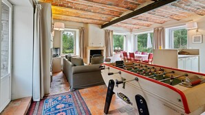 A cozy room with a foosball table, a fireplace, and a view of the outdoors.