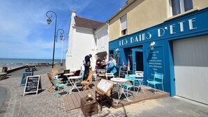 A seaside café with outdoor seating, a clear view of the sea, and a sign reading "LES BAIS D'ETE". - Modern flat in Bayeux in the town centre (Bayeux)