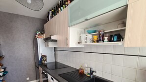 A modern kitchen with a black countertop, wooden cabinets, a built-in oven, and a wine rack on the wall. - Aquarium district, near Old Port, private parking (La Rochelle)
