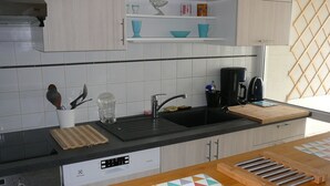 A modern kitchen with a black countertop, white cabinets, and a wooden cutting board. - Aquarium district, near Old Port, private parking (La Rochelle)