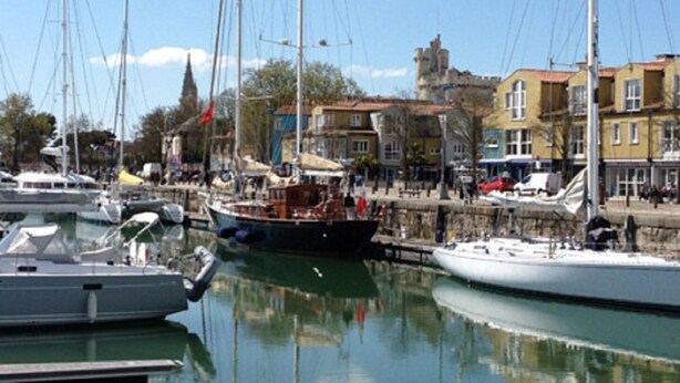 A marina with several sailboats docked, a wooden pier, and buildings in the background. - Aquarium district, near Old Port, private parking (La Rochelle)