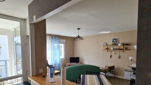 A modern living room with a large window, a green sofa, a wooden coffee table, and a TV. - Aquarium district, near Old Port, private parking (La Rochelle)