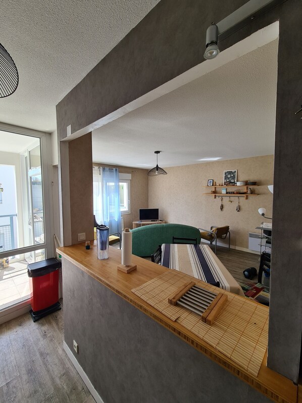 A modern living room with a large window, a green sofa, a wooden coffee table, and a TV. - Aquarium district, near Old Port, private parking (La Rochelle)