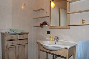 A bathroom with a sink, mirror, and wooden cabinet.