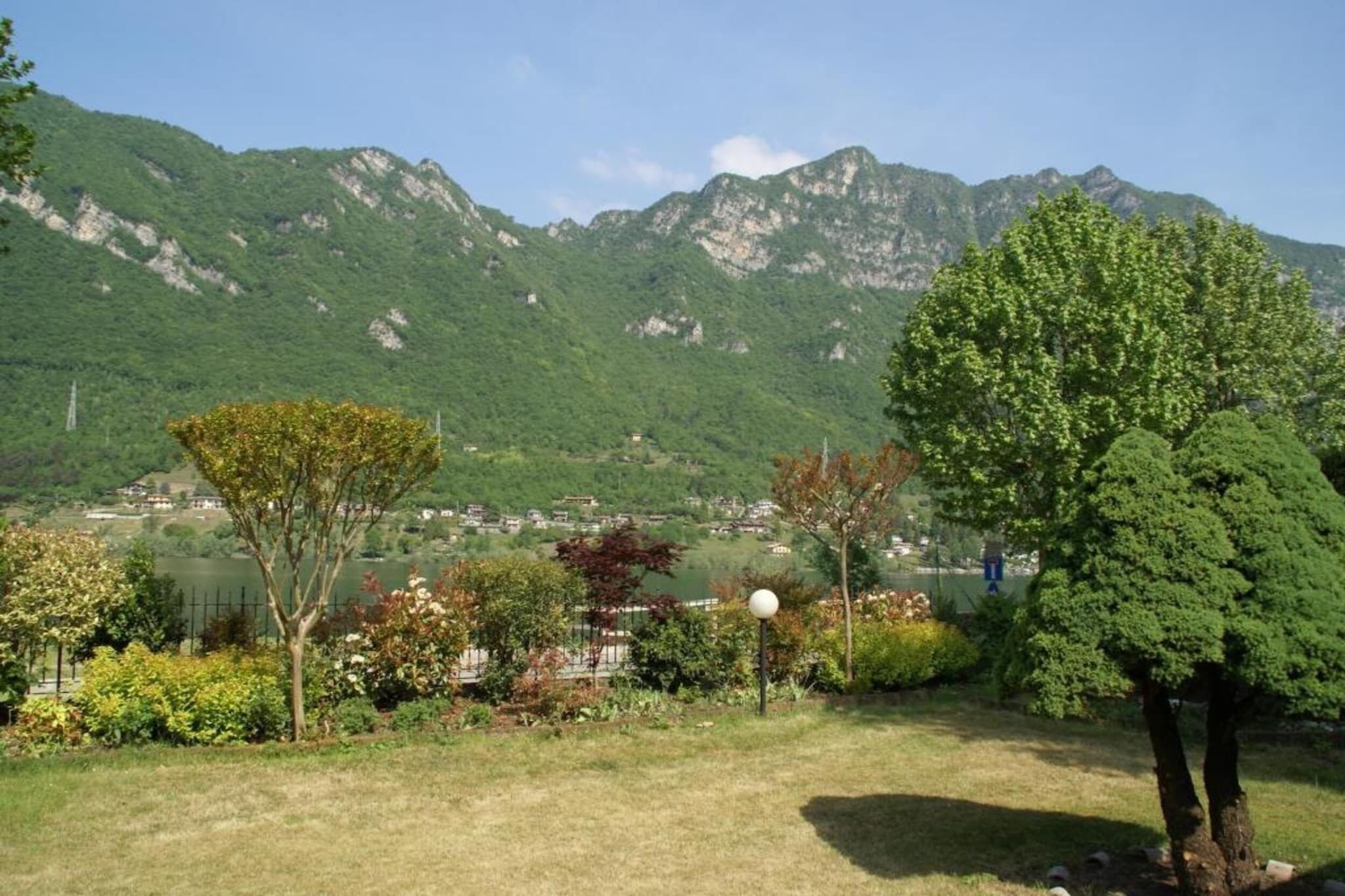 Un paysage montagneux avec un lac, des arbres et un petit village situé dans la vallée.