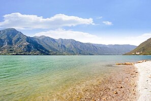 A clear lake with a rocky shoreline and mountains in the background.