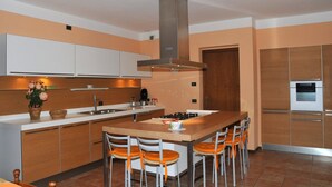 Una cocina moderna con una isla central, taburetes de bar y electrodomésticos integrados.