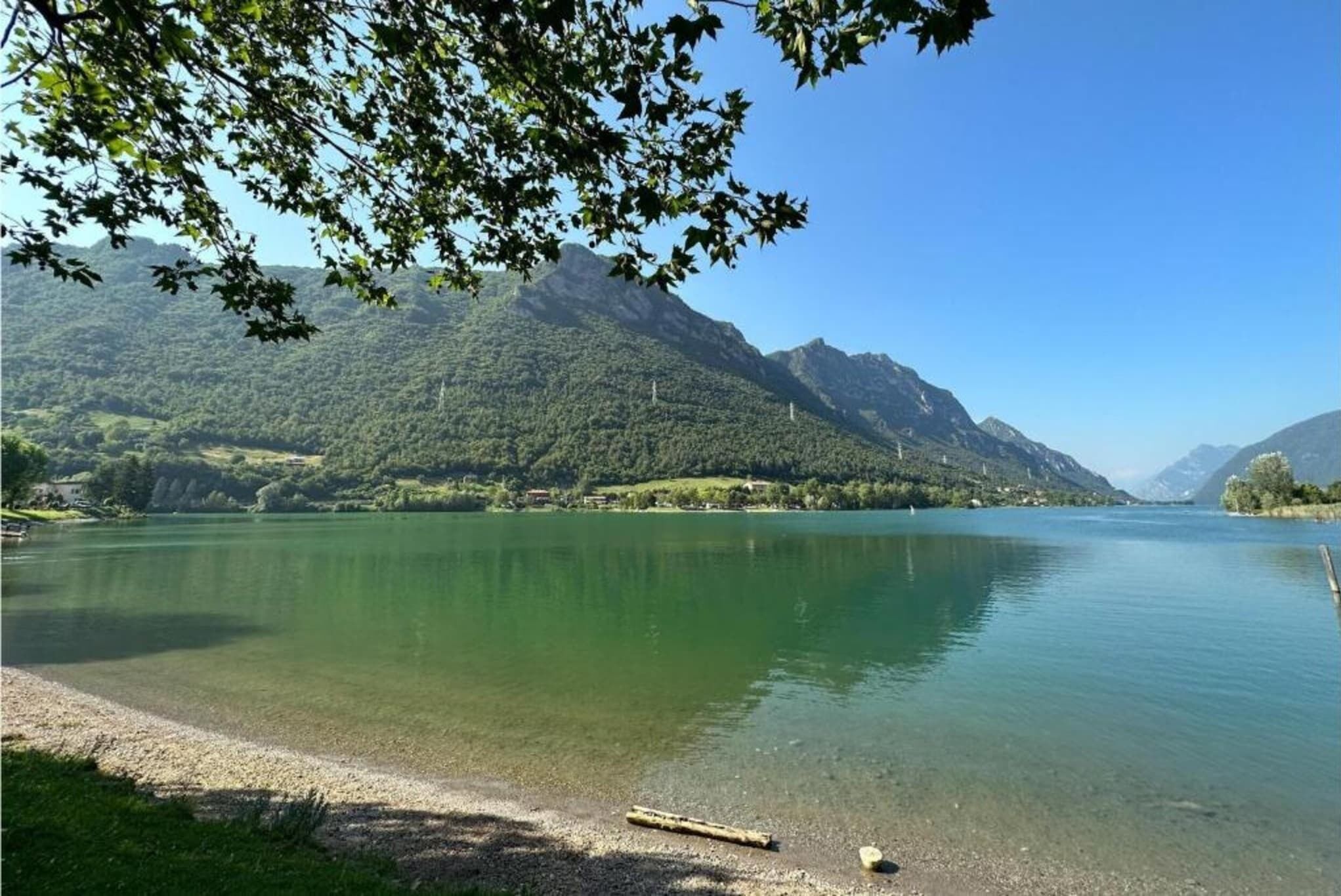 A calm lake with mountains in the background and a clear sky.