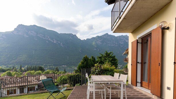 A patio with a table and chairs, a green folding chair, and a view of mountains. - Holiday Home in Idro near Scenic Hills (Idro (bs))