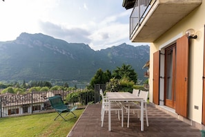 A patio with a table and chairs, a green folding chair, and a view of mountains. - Holiday Home in Idro near Scenic Hills (Idro (bs))