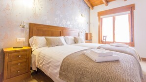 A bedroom with two beds, wooden headboard, bedside tables, and a window with daylight. - Casa da Ponte de Penas (Melide)