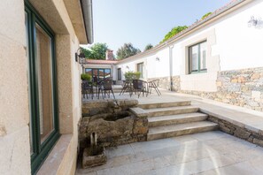 A stone staircase leading to a patio area with outdoor seating. - Casa da Ponte de Penas (Melide)